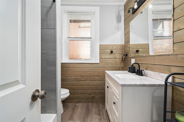 full bathroom with toilet, wood finished floors, vanity, and wooden walls