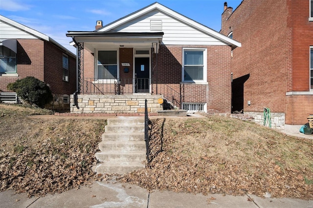 bungalow-style home featuring covered porch and brick siding