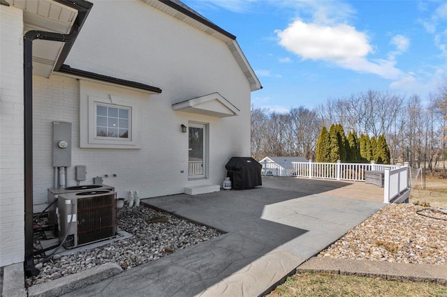 exterior space featuring central AC unit, a patio area, fence, and brick siding