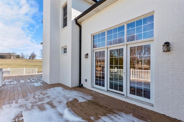 view of exterior entry with brick siding and a wooden deck