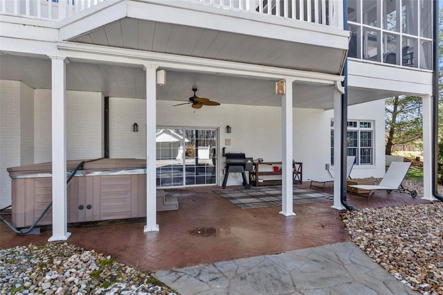 view of patio with a balcony, a ceiling fan, and a hot tub