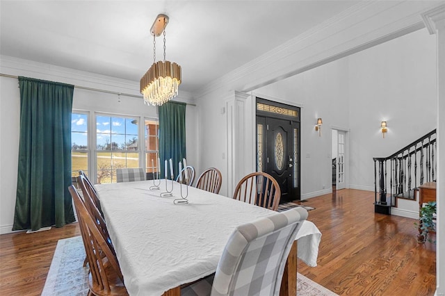 dining area with ornamental molding, a chandelier, stairway, and wood finished floors