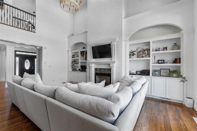 living area featuring a chandelier, visible vents, a high end fireplace, built in features, and dark wood-style floors