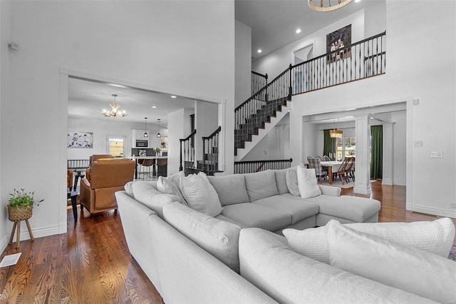 living room featuring a notable chandelier, visible vents, stairway, wood finished floors, and baseboards