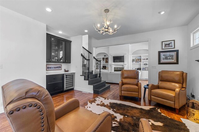 living area with wine cooler, a fireplace, stairway, a dry bar, and dark wood finished floors