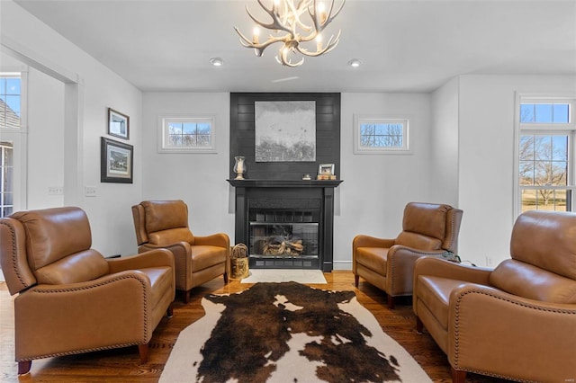 living area featuring a notable chandelier, a fireplace, and wood finished floors