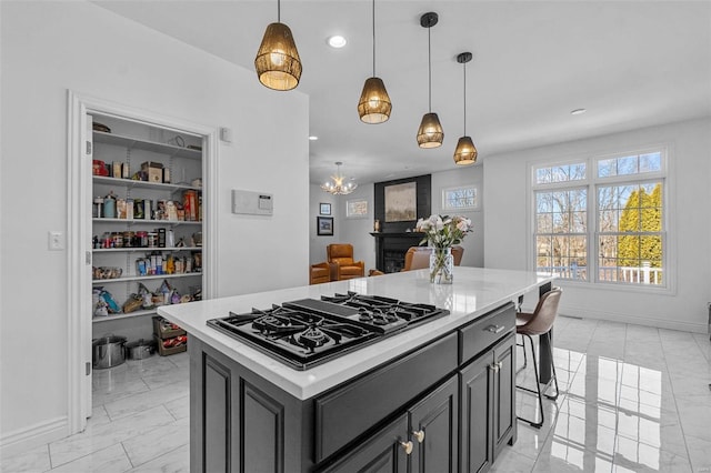 kitchen featuring baseboards, decorative light fixtures, light countertops, black gas stovetop, and recessed lighting