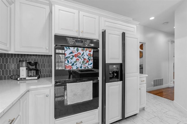 kitchen with white cabinets, dobule oven black, visible vents, and decorative backsplash