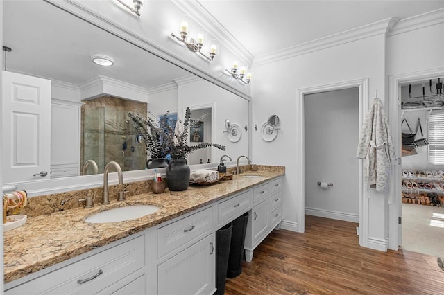 bathroom featuring ornamental molding, a sink, a shower stall, and wood finished floors