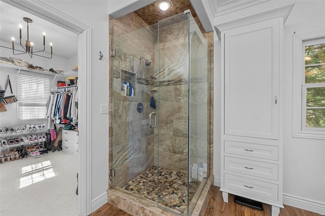 full bath with wood finished floors, a shower stall, baseboards, and a spacious closet