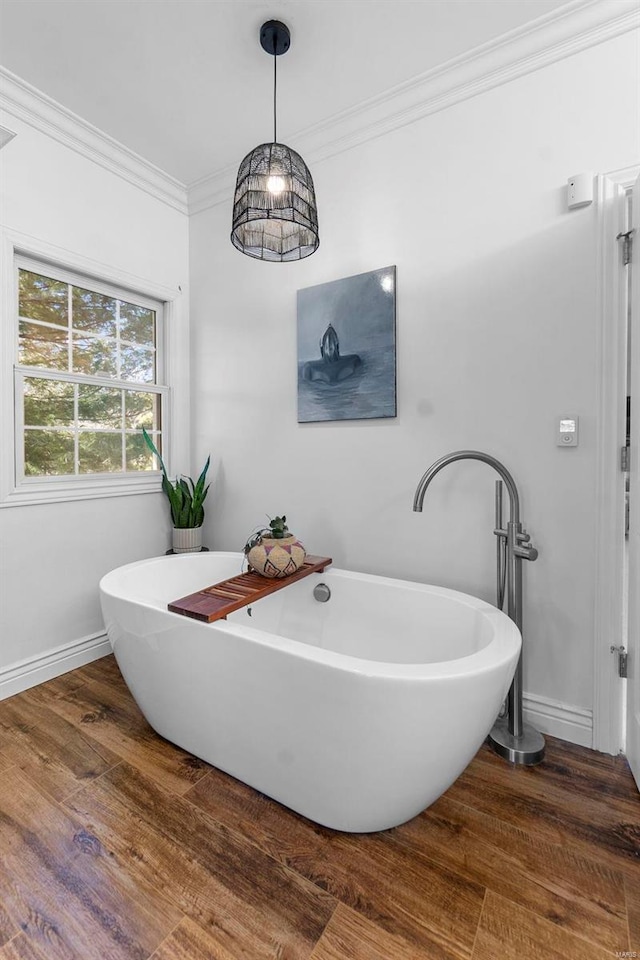 bathroom with a soaking tub, baseboards, ornamental molding, and wood finished floors