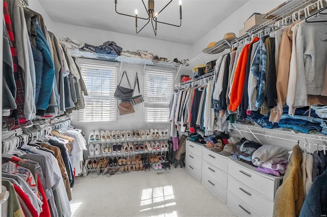 walk in closet with carpet flooring and a notable chandelier