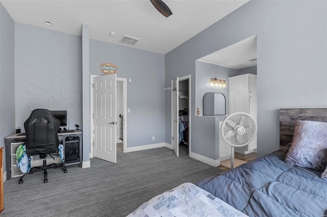 carpeted bedroom with a ceiling fan, visible vents, a spacious closet, and baseboards