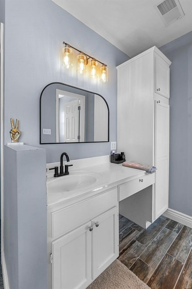 bathroom featuring wood finish floors, vanity, visible vents, and baseboards