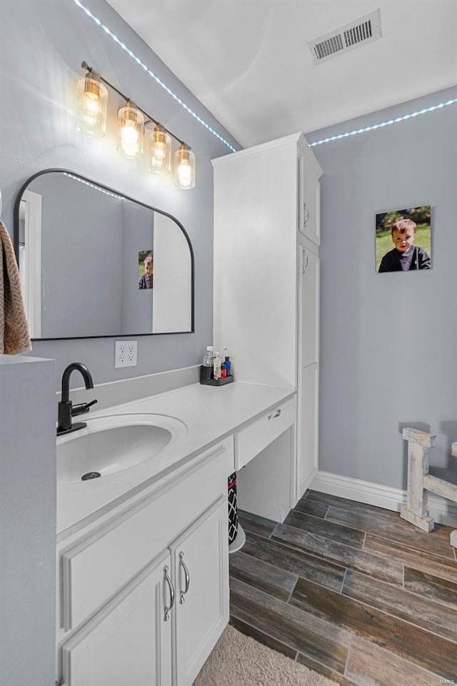 bathroom with wood tiled floor, visible vents, baseboards, and vanity