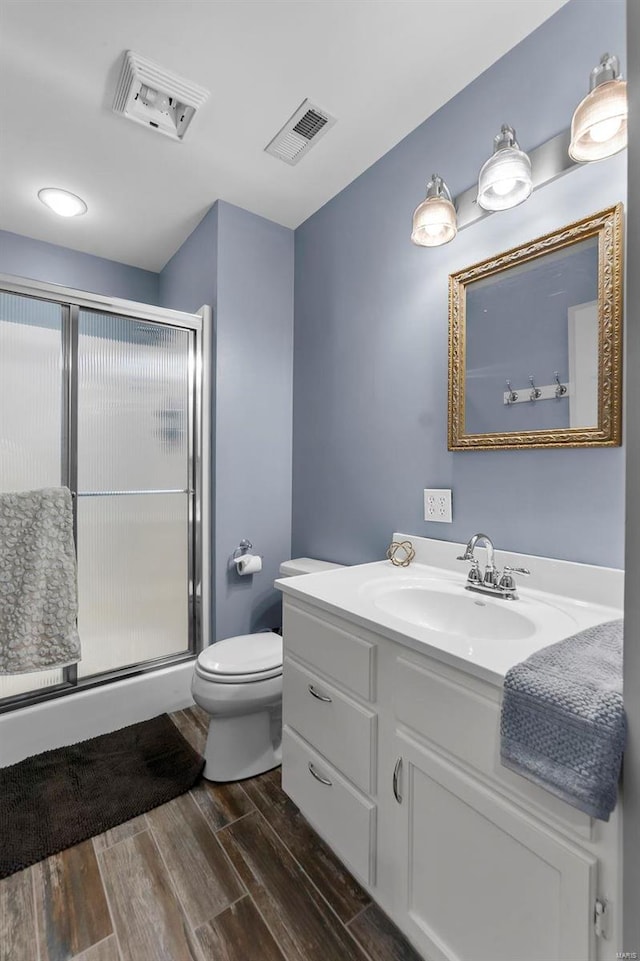 full bathroom featuring toilet, a stall shower, wood tiled floor, and visible vents