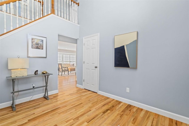 interior space with a high ceiling, baseboards, and wood finished floors