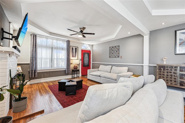 living room featuring a ceiling fan, hardwood / wood-style flooring, a tray ceiling, recessed lighting, and a fireplace