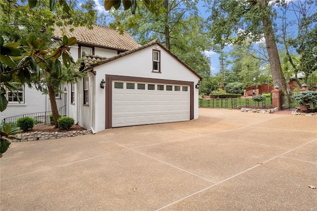 garage featuring fence and concrete driveway