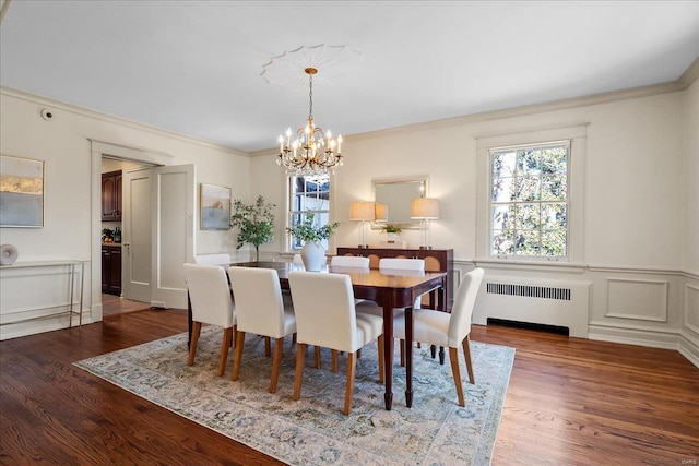 dining room with crown molding, radiator heating unit, wood finished floors, and a healthy amount of sunlight