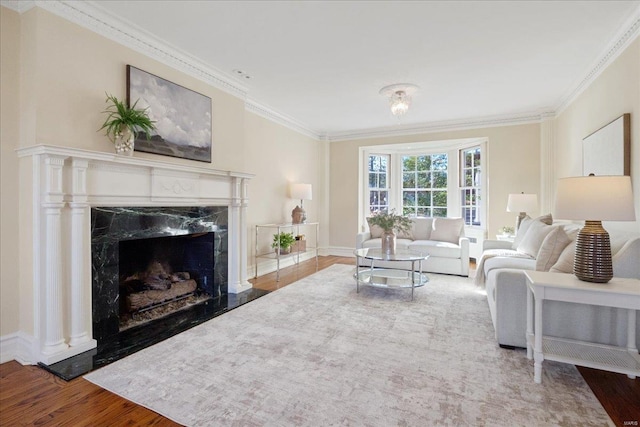 living room featuring baseboards, a fireplace, ornamental molding, and wood finished floors