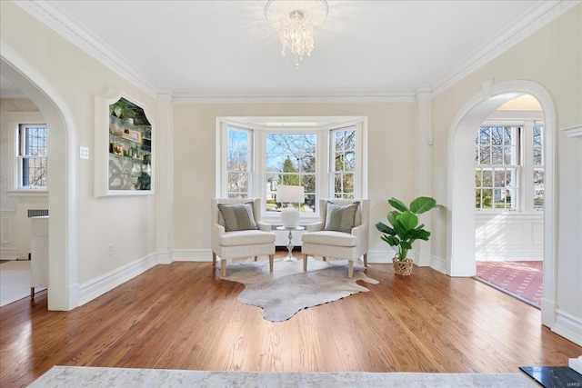 sitting room featuring ornamental molding, a wealth of natural light, and wood finished floors