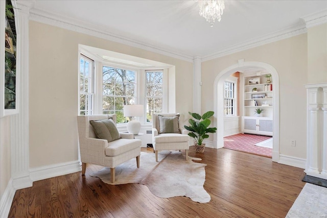 sitting room featuring built in shelves, wood finished floors, and crown molding