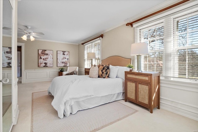 bedroom featuring a wainscoted wall, ornamental molding, a decorative wall, and light colored carpet