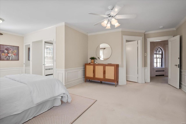 bedroom with radiator, a wainscoted wall, light colored carpet, and multiple windows