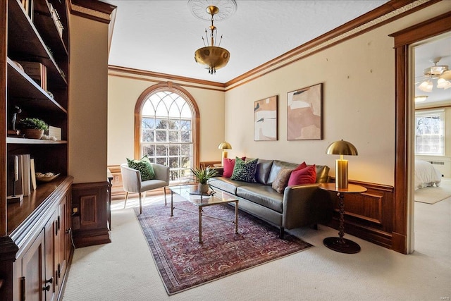 sitting room with a wainscoted wall, light carpet, crown molding, and a healthy amount of sunlight