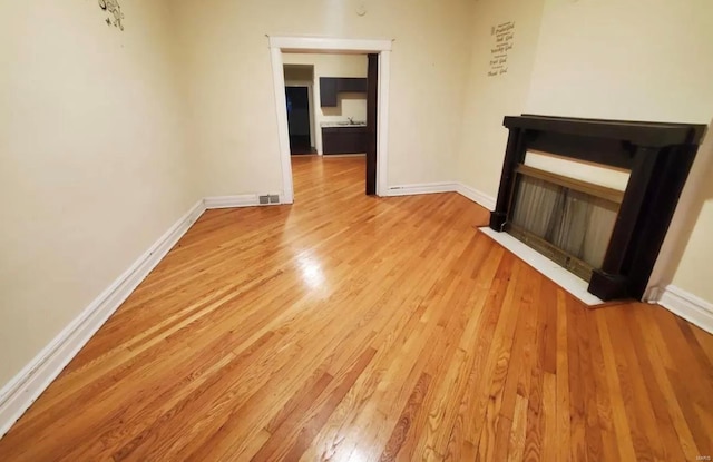 unfurnished living room with visible vents, light wood-style flooring, and baseboards