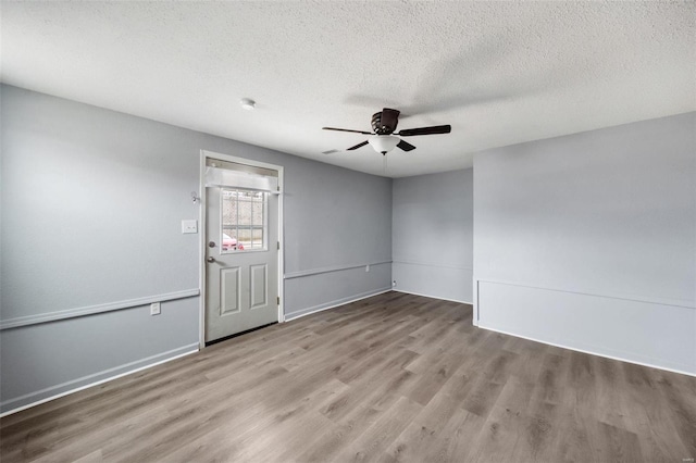 spare room with ceiling fan, a textured ceiling, wood finished floors, and baseboards