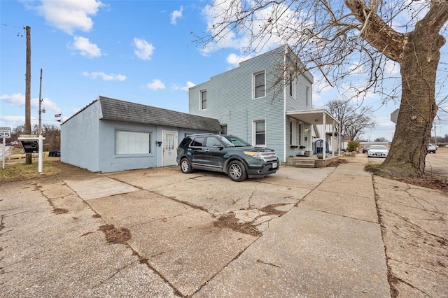 rear view of house with a shingled roof and concrete driveway