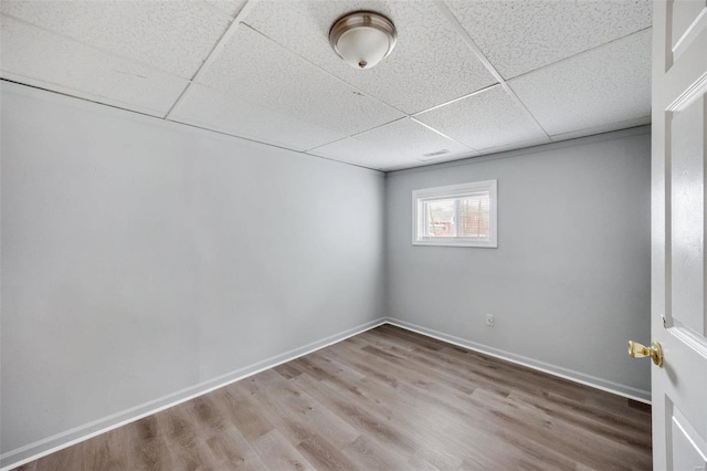 empty room with a paneled ceiling, baseboards, and wood finished floors