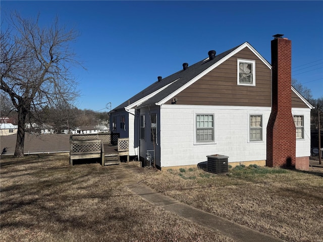 rear view of property with a chimney, a lawn, a deck, and central AC