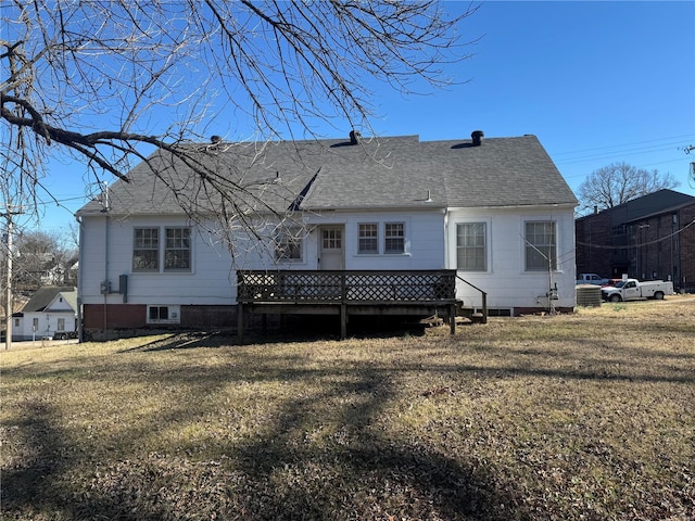 back of property featuring roof with shingles, a lawn, and a wooden deck