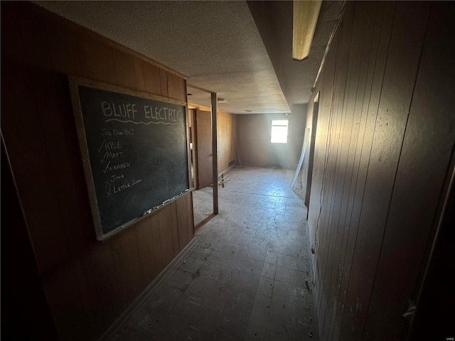 hall with wooden walls and a textured ceiling