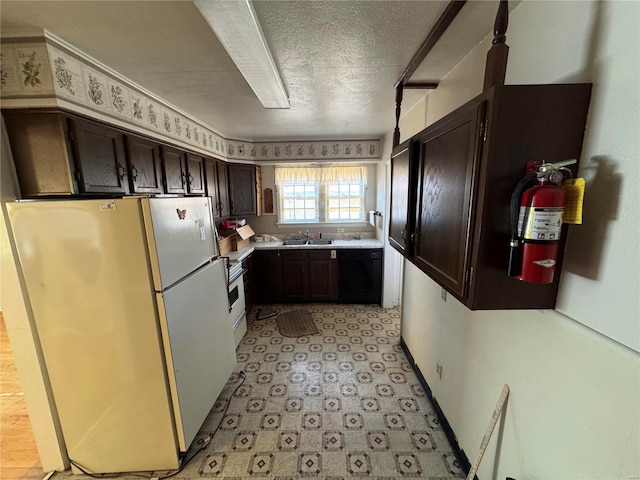 kitchen featuring black dishwasher, freestanding refrigerator, light countertops, dark brown cabinets, and a sink