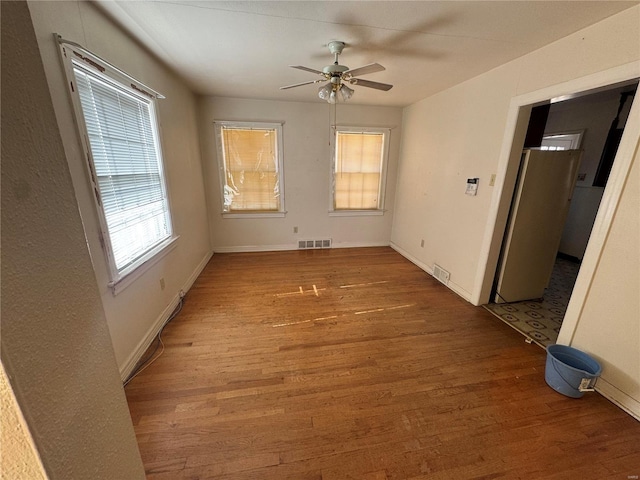 spare room featuring visible vents, ceiling fan, baseboards, and wood finished floors