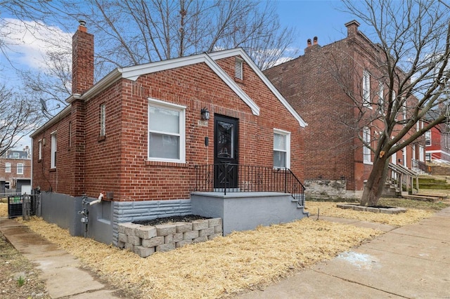 view of front facade featuring brick siding and a chimney