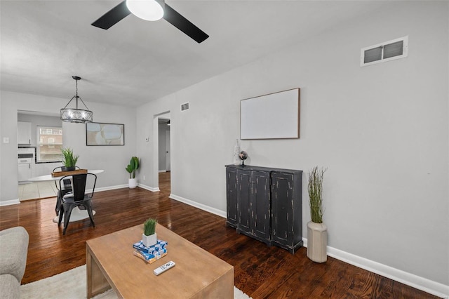 living area with baseboards, visible vents, and wood finished floors