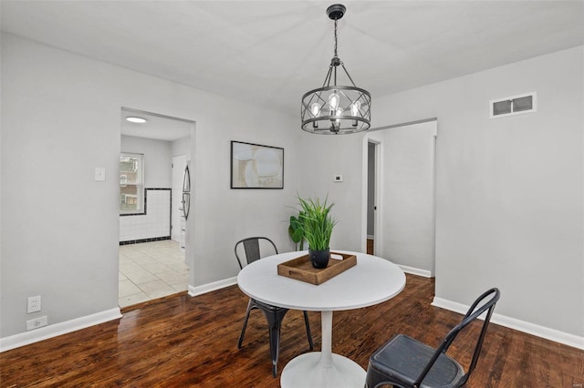 dining room with baseboards, wood finished floors, visible vents, and an inviting chandelier