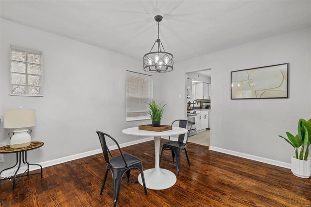 dining space with a notable chandelier, baseboards, and wood finished floors