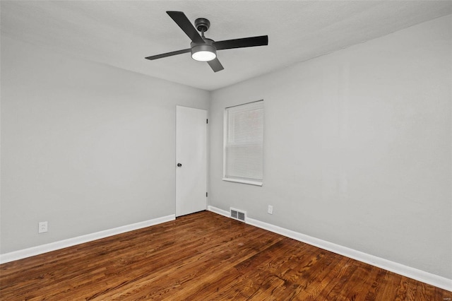 spare room with visible vents, wood finished floors, a ceiling fan, and baseboards