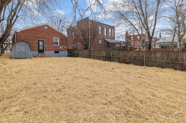 view of yard featuring entry steps, a storage shed, an outbuilding, and fence