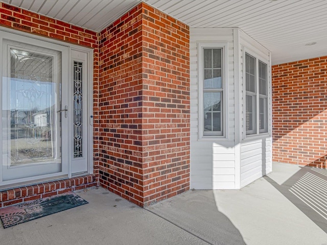 property entrance featuring a porch and brick siding