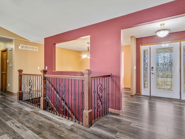 foyer with a textured wall, wood finished floors, visible vents, and baseboards