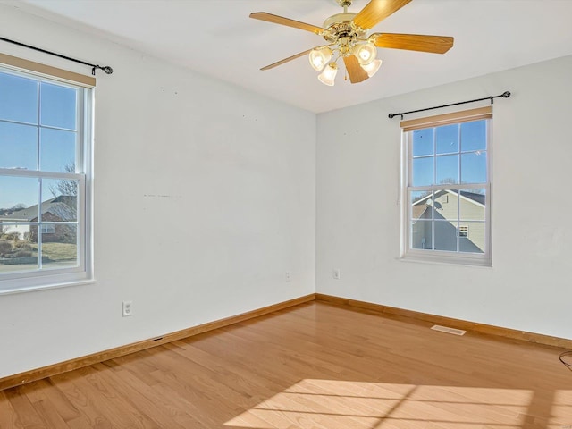 spare room featuring a wealth of natural light, visible vents, and wood finished floors