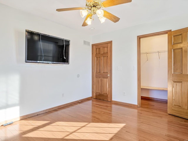 unfurnished bedroom with baseboards, visible vents, a spacious closet, light wood-type flooring, and a closet