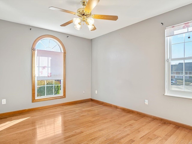 unfurnished room featuring baseboards, light wood finished floors, and a healthy amount of sunlight